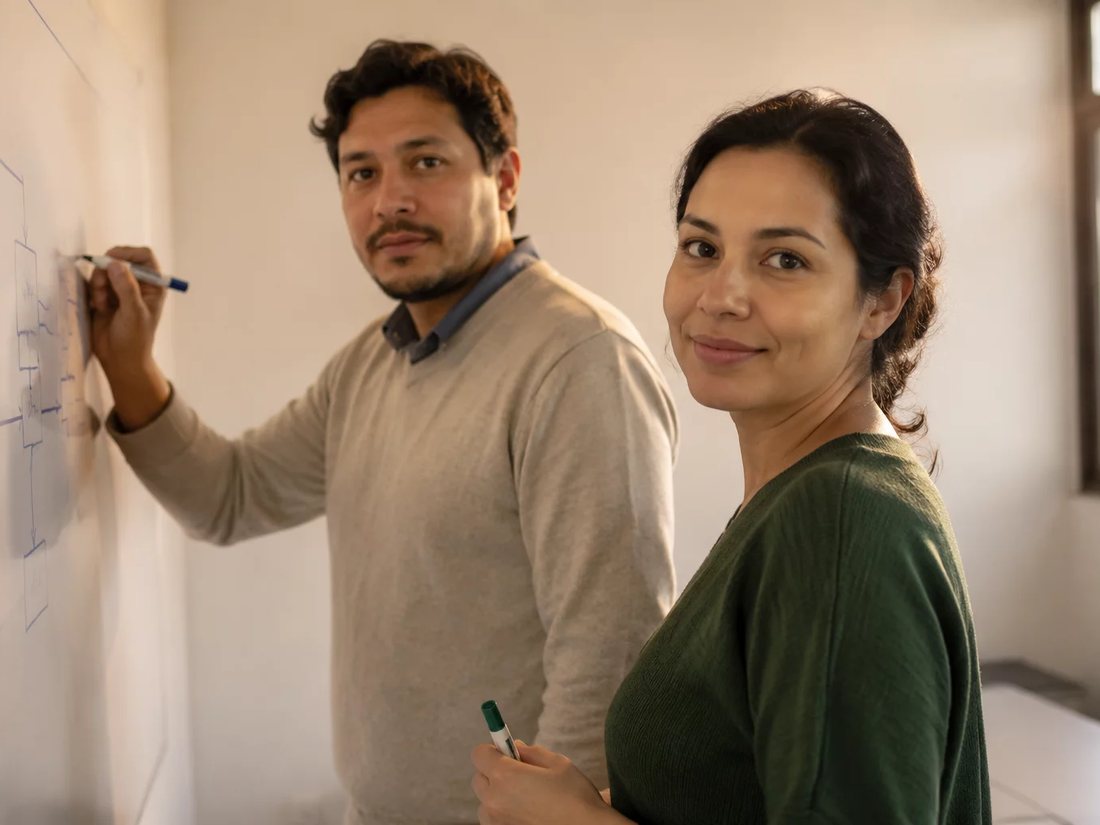 Dois alunos em pé diante do quadro branco, desenhando a ordem de um argumento